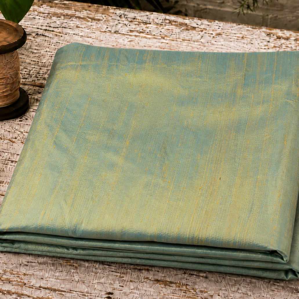 Aqua Gold Dupion Silk Fabric folded to showcase its soft aqua-blue colour, subtle golden iridescence, natural silk texture, and lustrous sheen