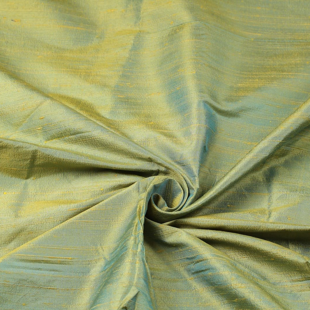 Aqua Gold Dupion Silk Fabric arranged in elegant swirling folds highlighting its luminous sheen, natural slub texture, and shimmering aqua-gold tones