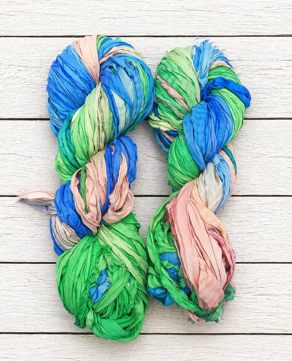 Full skein of Seaside Garden sari silk ribbon yarn in blue, green and blush tones