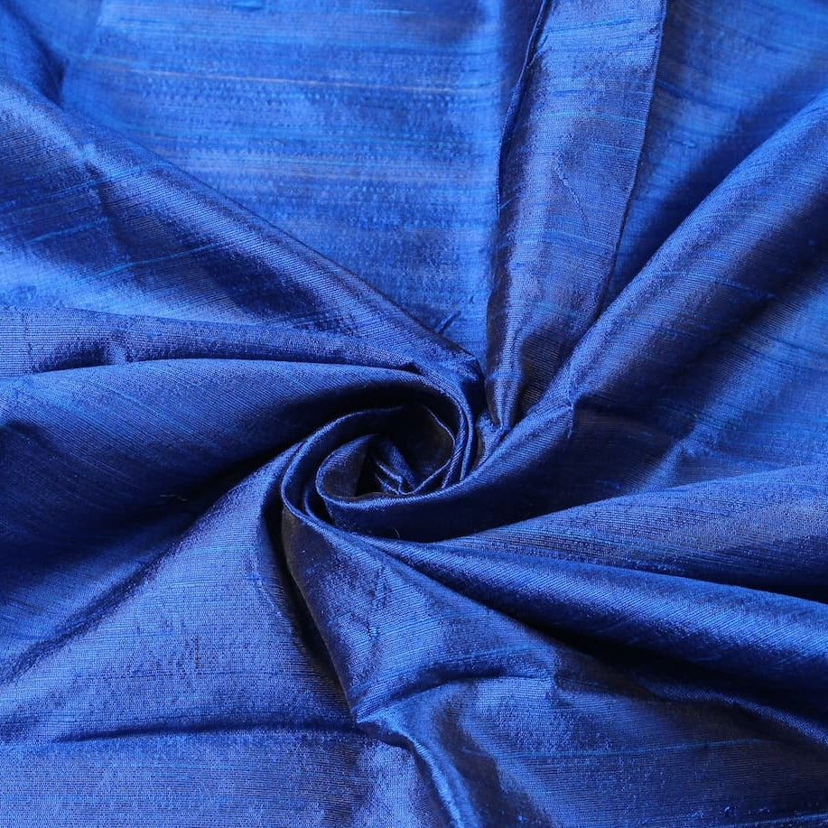 Royal Blue Dupion Silk Fabric arranged in elegant swirling folds highlighting its luminous sheen, crisp texture, and rich blue tones