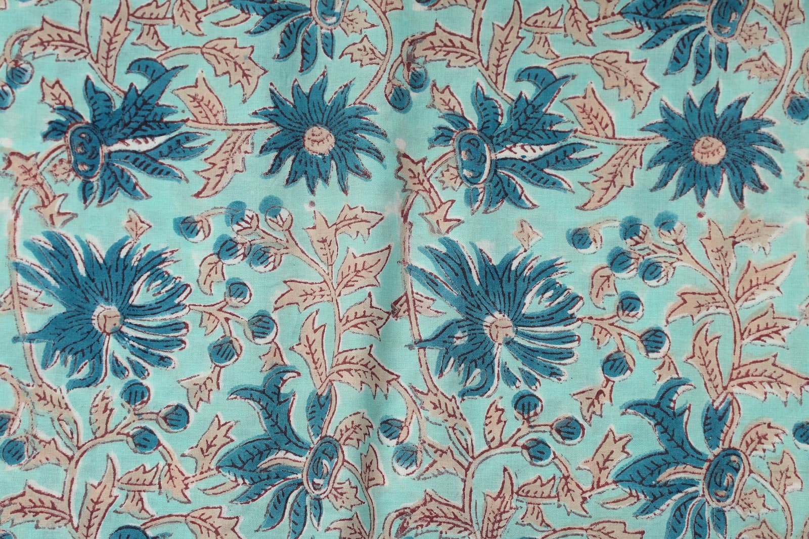 Close-up of blue floral blooms and delicate vine details on aqua hand block printed cotton fabric