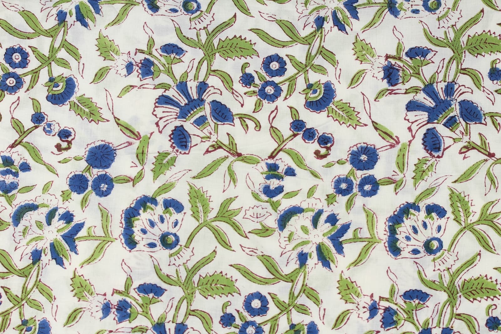 Close-up of blue floral motifs and green leafy vines on hand block printed cotton fabric