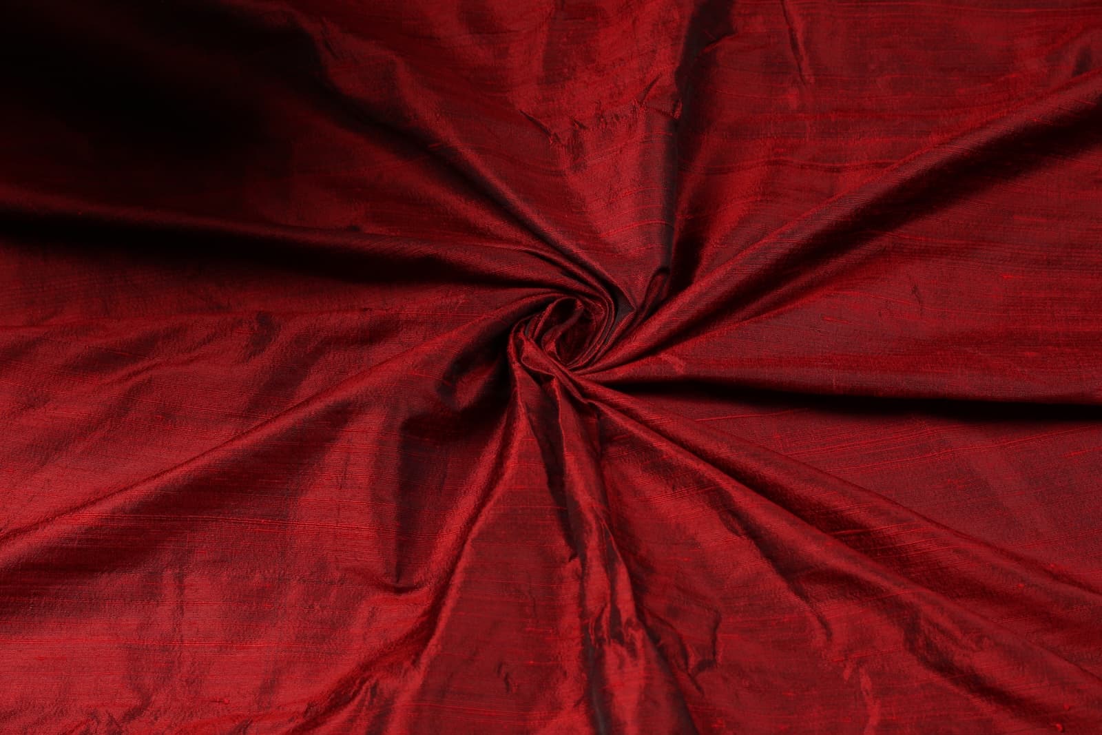 Bordeaux Red Dupion Silk Fabric arranged in elegant swirling folds highlighting its lustrous finish and natural silk texture