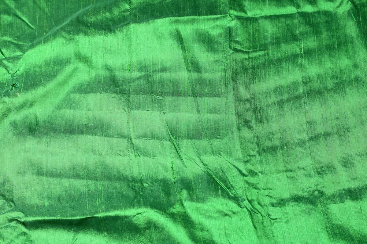 Spring Green Dupion Silk Fabric displayed with soft folds revealing natural silk texture, luminous sheen, and rich fresh green colouring