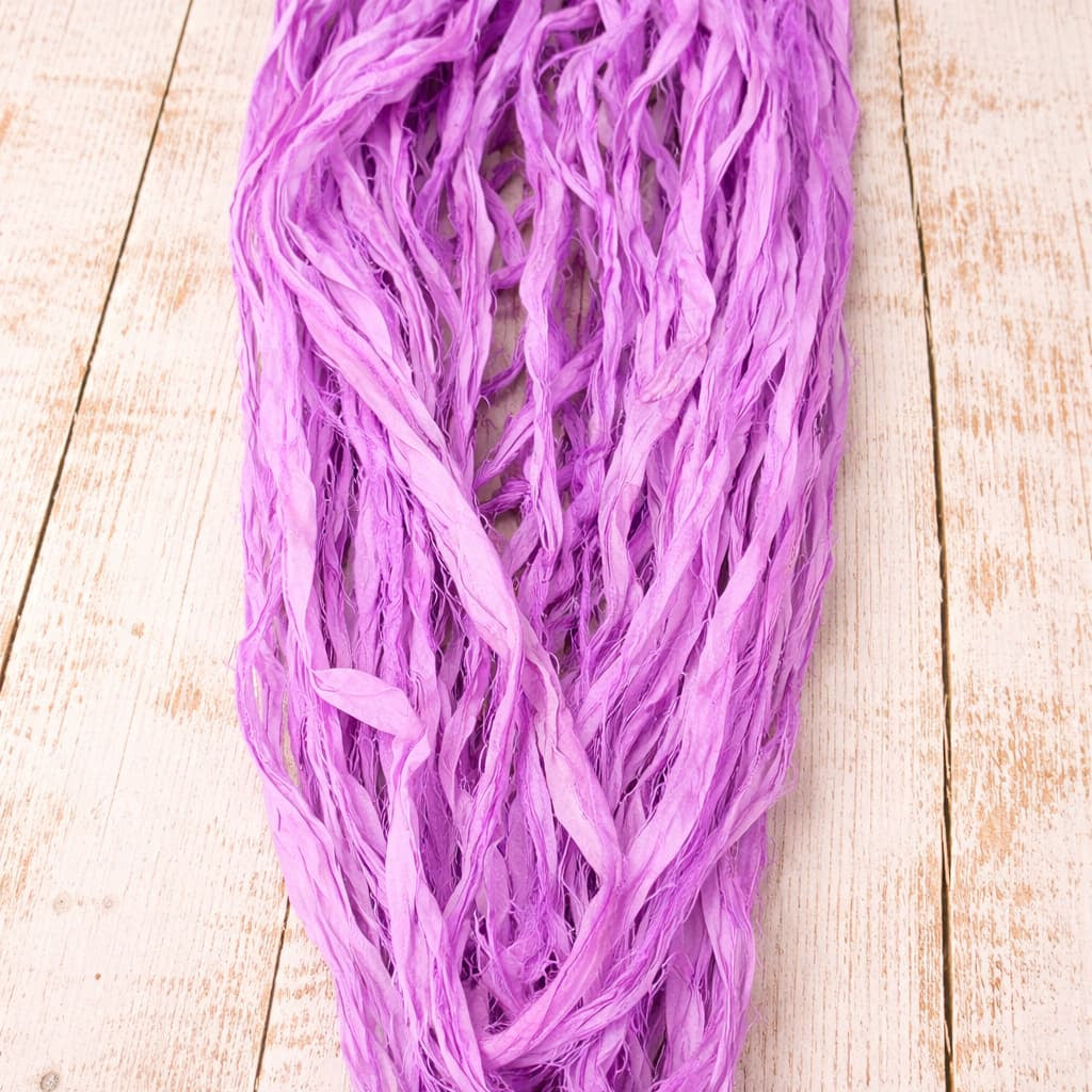 Orchid sari silk ribbon in loose strands showing soft texture and naturally frayed edges.