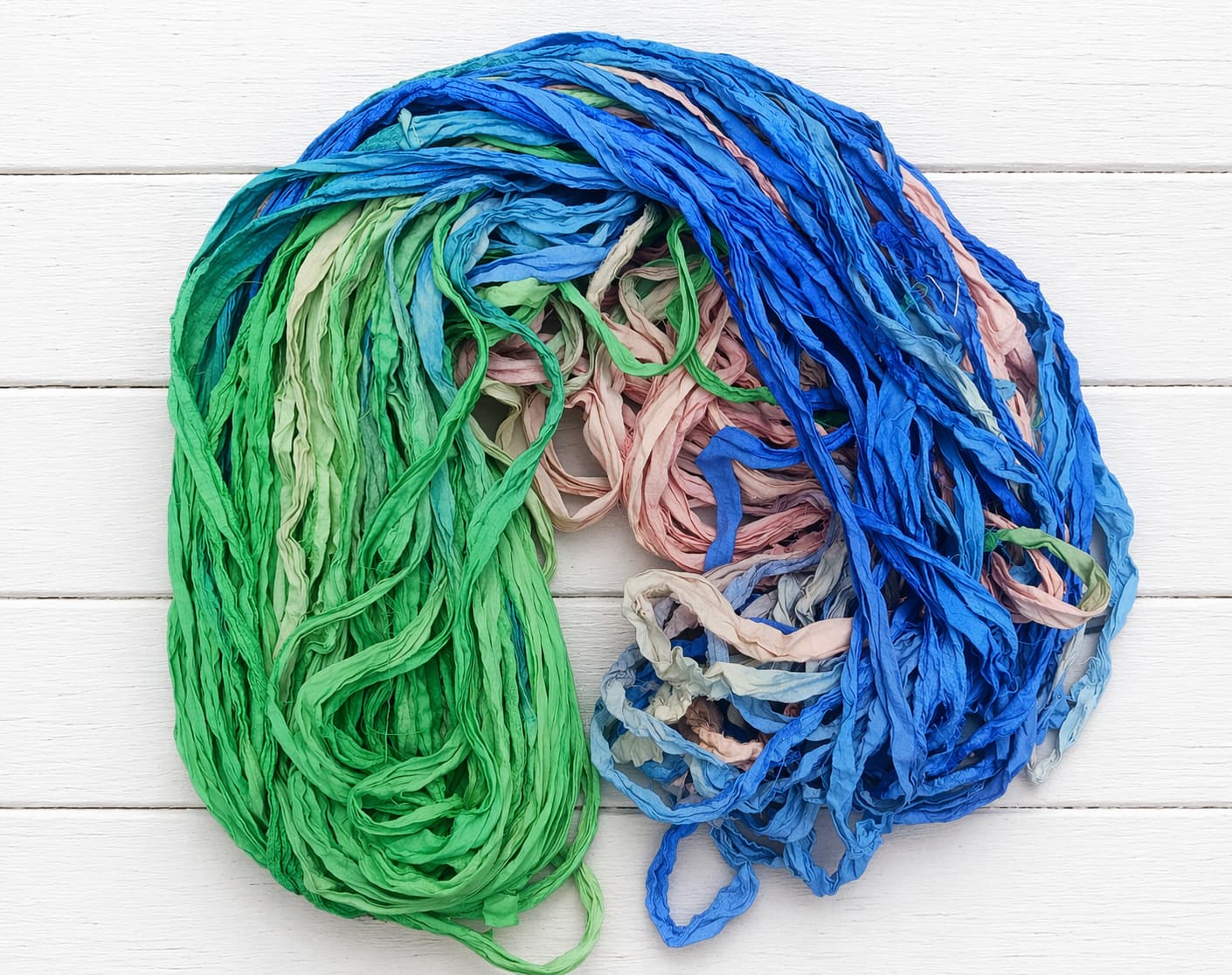 Loose strands of Seaside Garden recycled silk ribbon yarn with ocean-inspired colors
