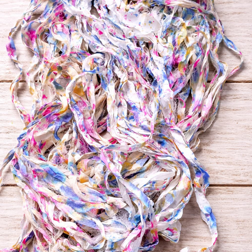 Loose strands of Cotton Candy Confetti sari silk ribbon yarn showing watercolor-inspired colors