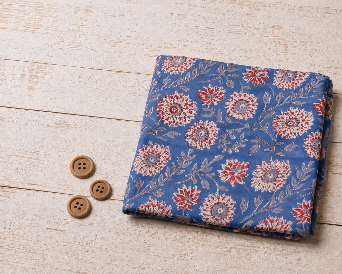 Cornflower Dahlia block printed cotton fabric folded on a whitewashed wooden surface with wooden buttons