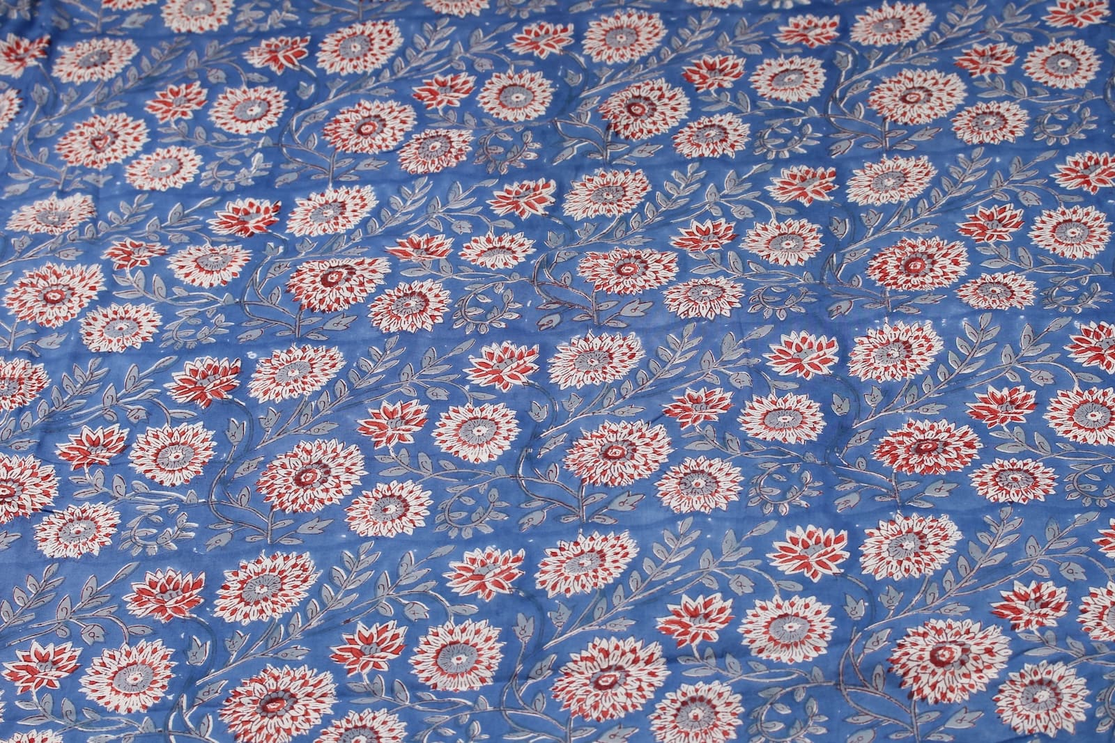 Cornflower Dahlia hand block printed cotton fabric featuring red and ivory dahlia flowers on a cornflower blue background