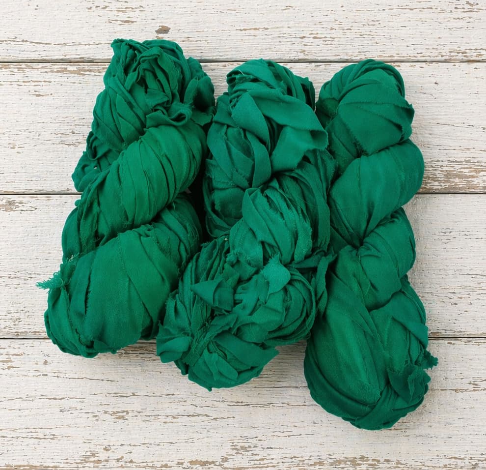 Multiple skeins of emerald chiffon silk ribbon yarn arranged together