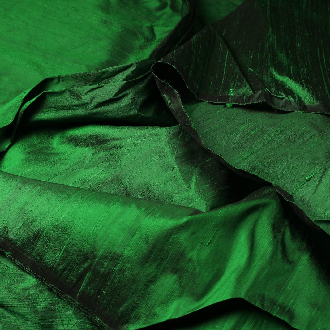 Close-up of Emerald Green Dupion Silk Fabric showing natural slub texture, woven silk detail, and rich emerald green colour