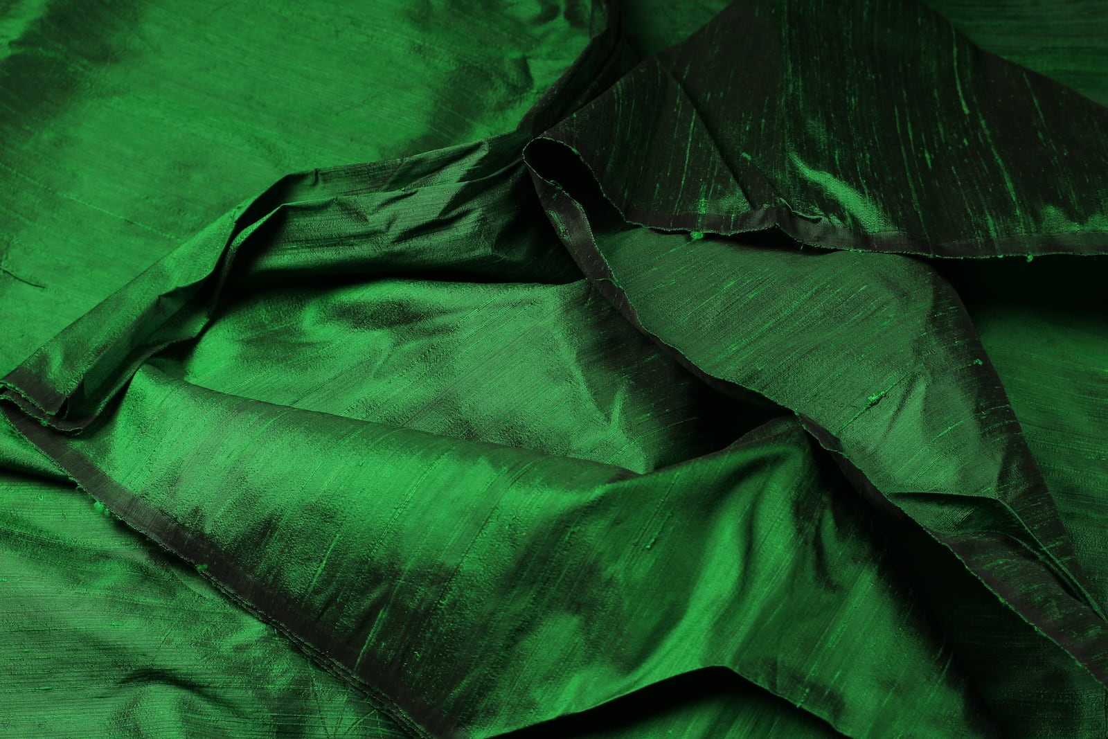 Close-up of Emerald Green Dupion Silk Fabric showing natural slub texture, woven silk detail, and rich emerald green colour