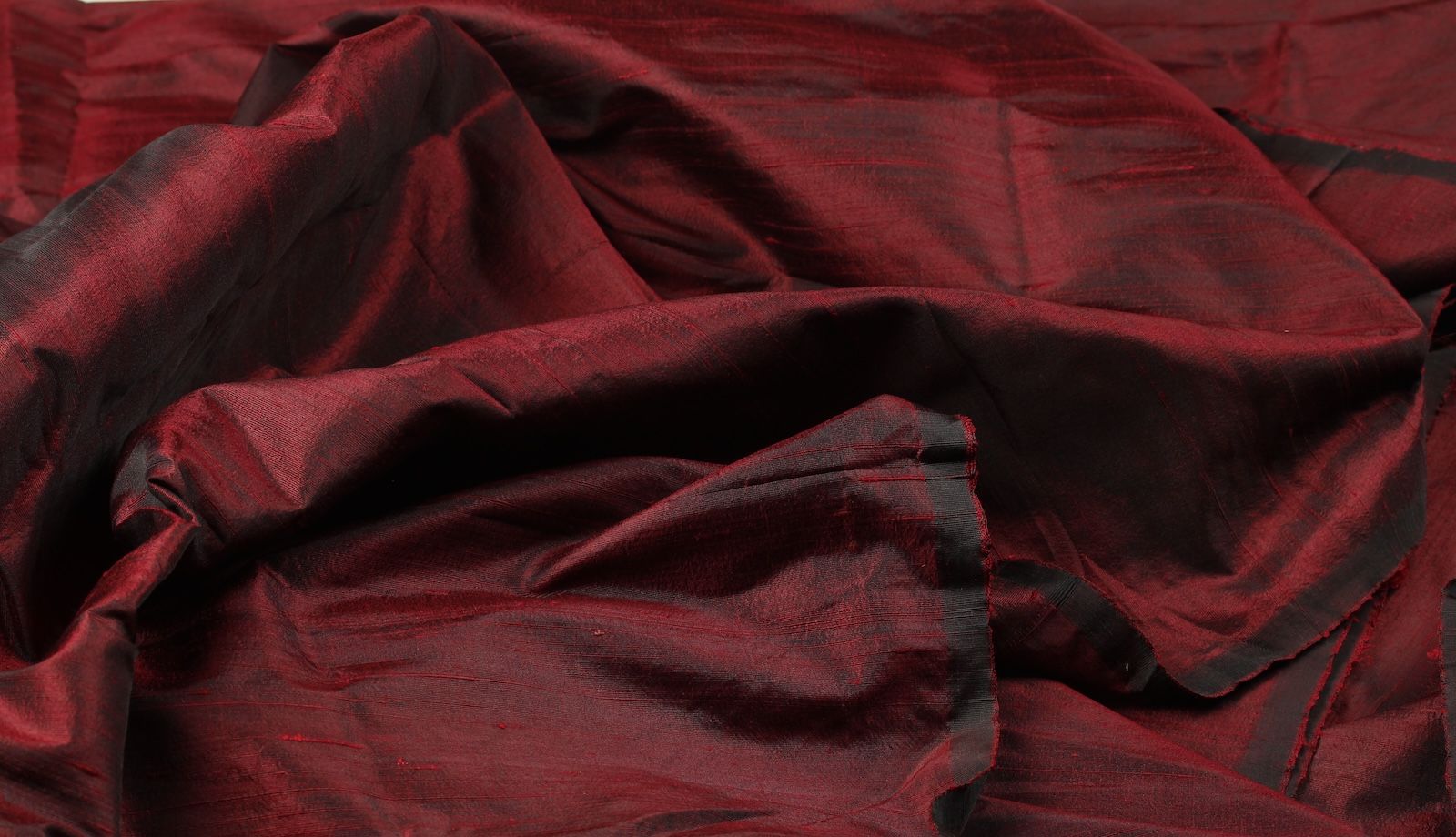 Ruby red raw silk fabric displaying the crisp drape of Dupion silk.