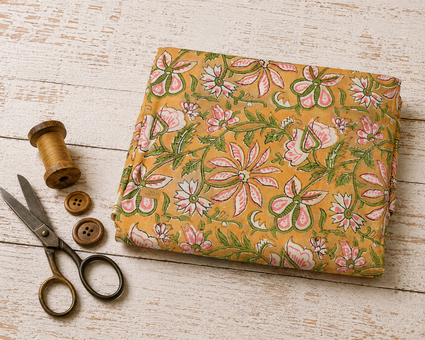 Folded golden mustard hand block printed cotton fabric with pink floral blossoms and green vine motifs