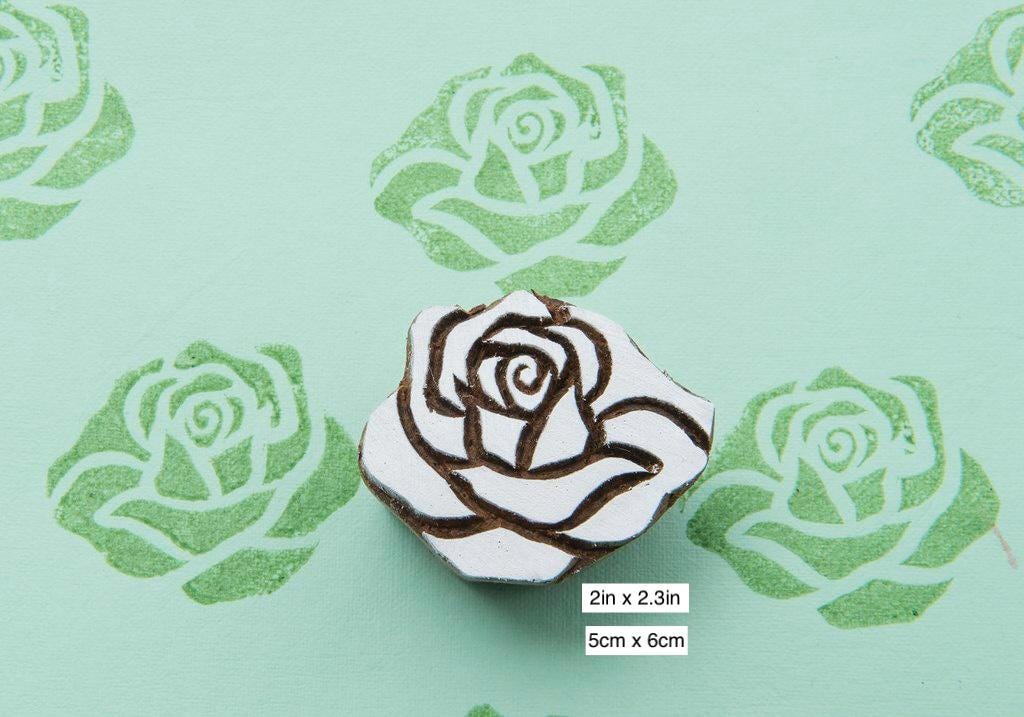 Hand carved rose wooden printing stamp creating repeating rose pattern on fabric.