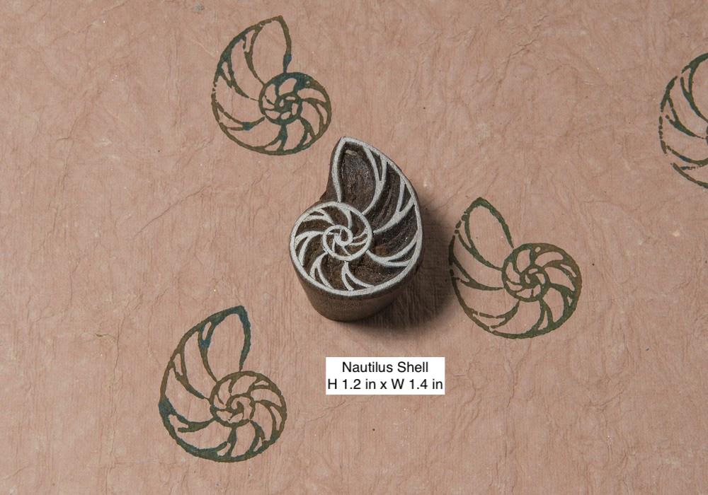 Hand carved nautilus shell wooden printing block shown with repeated sea life prints on handmade paper.