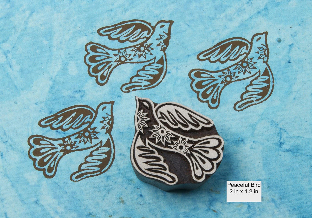 Decorative peaceful bird wood block stamp with floral details printed on blue handmade paper.