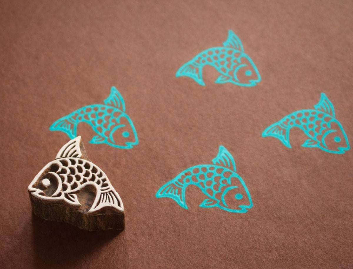 Hand carved fish wooden printing block with stamped blue images on brown craft paper...used for pottery, textile, paper block printing