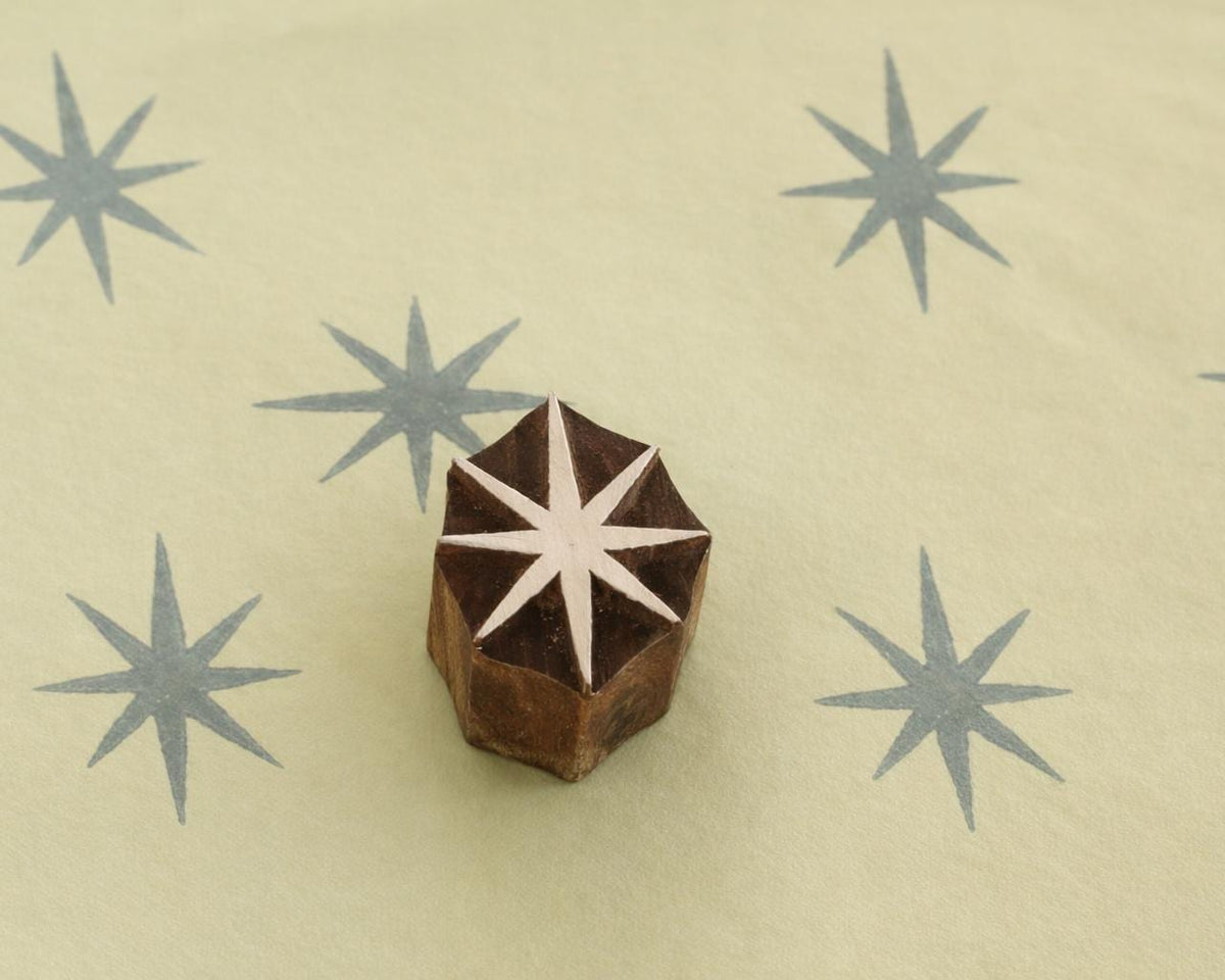 Hand carved 8 point star wooden block stamp printing grey starburst pattern on paper