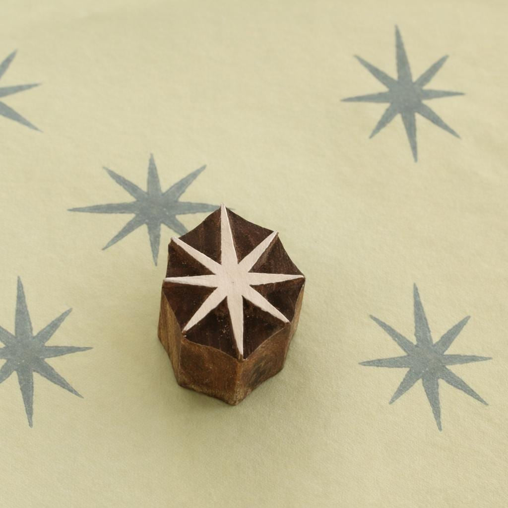 Hand carved 8 point star wooden block stamp printing grey starburst pattern on paper