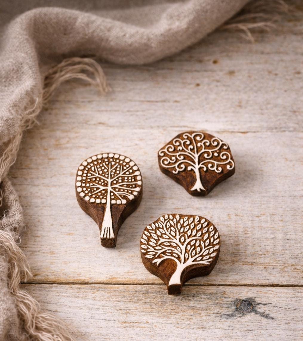 Three wooden tree-shaped stamps with detailed designs. The stamps are brown with white detailing, showcasing various tree styles. One stamp has a long handle, while the others are more compact. Suitable for block printing on paper, clay and textile