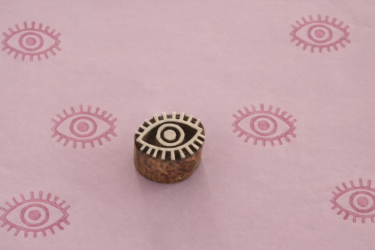 Carved wooden evil eye block stamp printing pink eye pattern on handmade paper