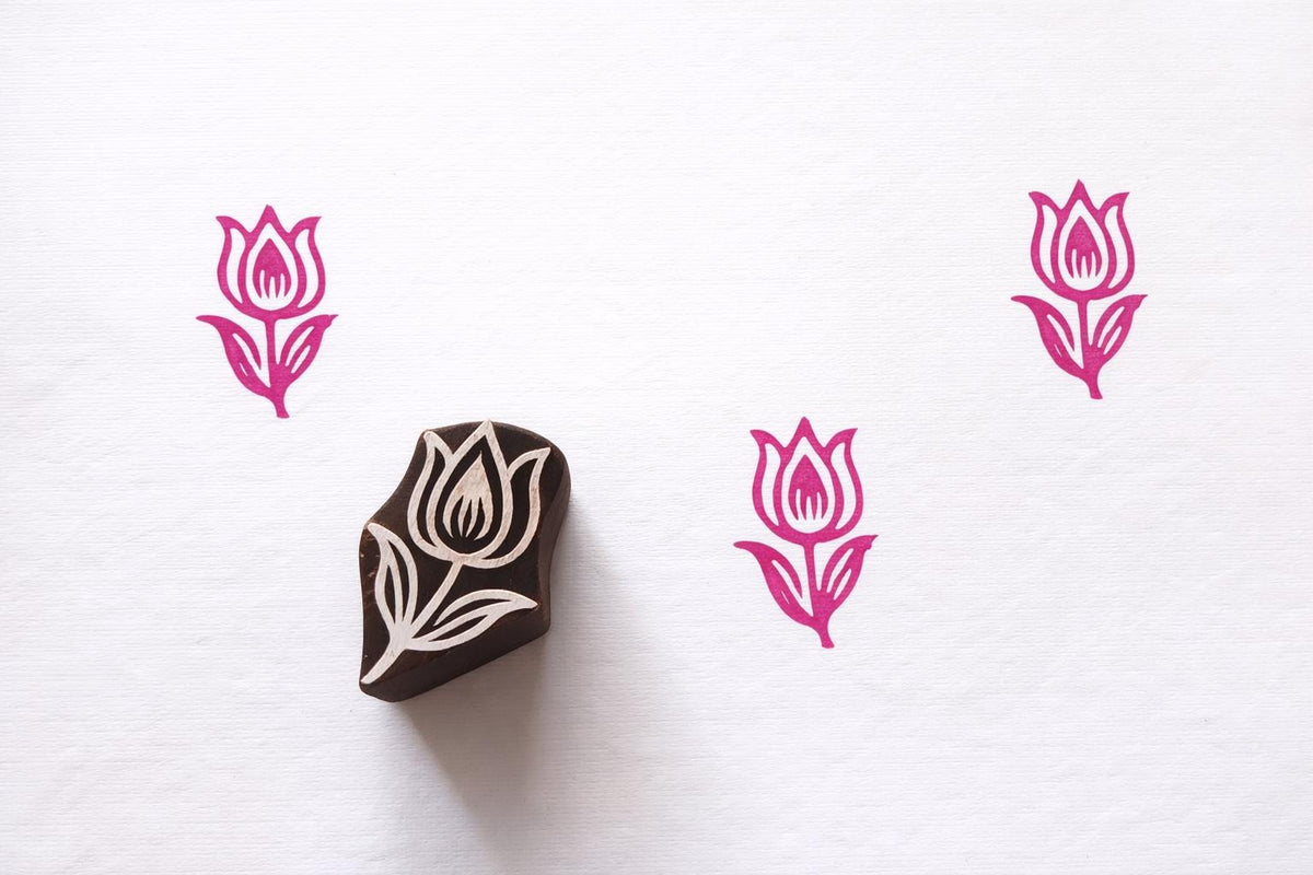 Hand carved tulip flower wooden block printing stamp creating pink tulip prints on white paper.