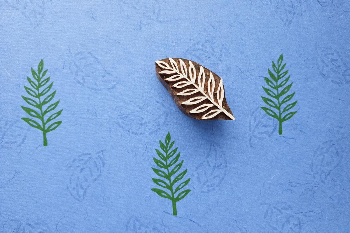 Leaf fabric stamp creating repeating green leaf prints using a hand carved wooden printing stamp.