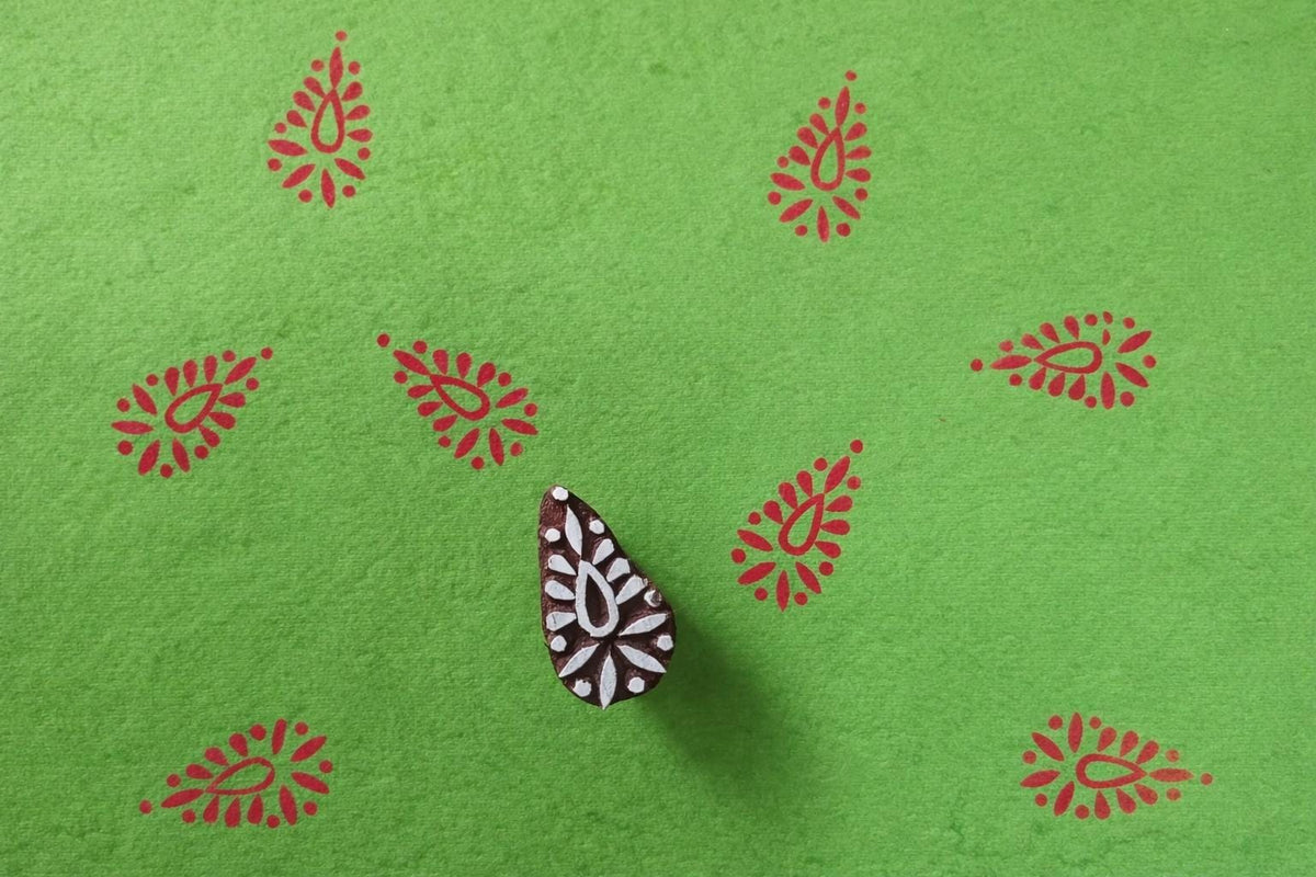 Jaipuri motif wooden printing block producing red prints on green paper.