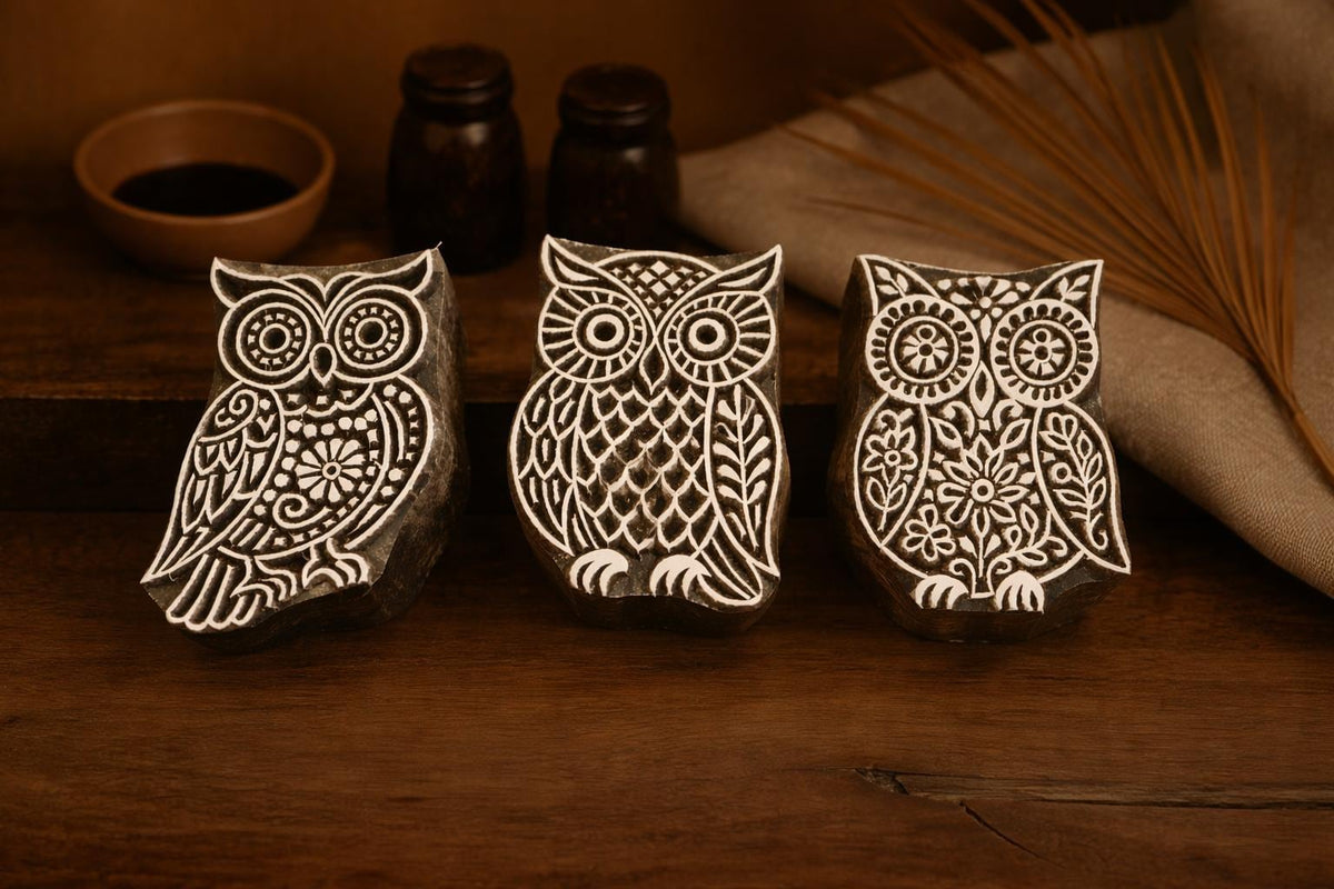 Set of three hand carved wooden owl stamps with detailed folk art patterns displayed on a rustic wooden surface