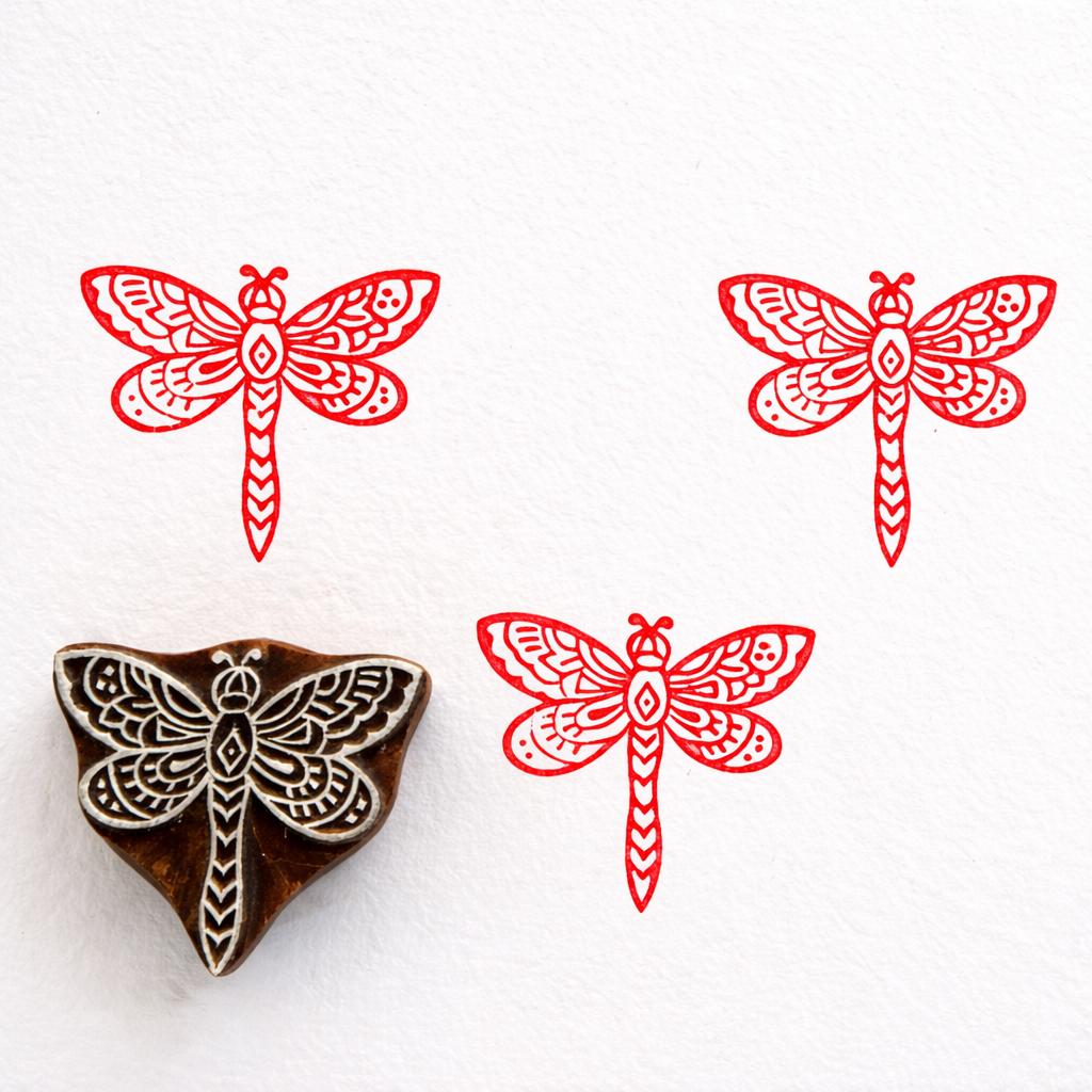 Hand carved wooden stamp featuring an ornate dragonfly with detailed patterned wings printed in red ink
