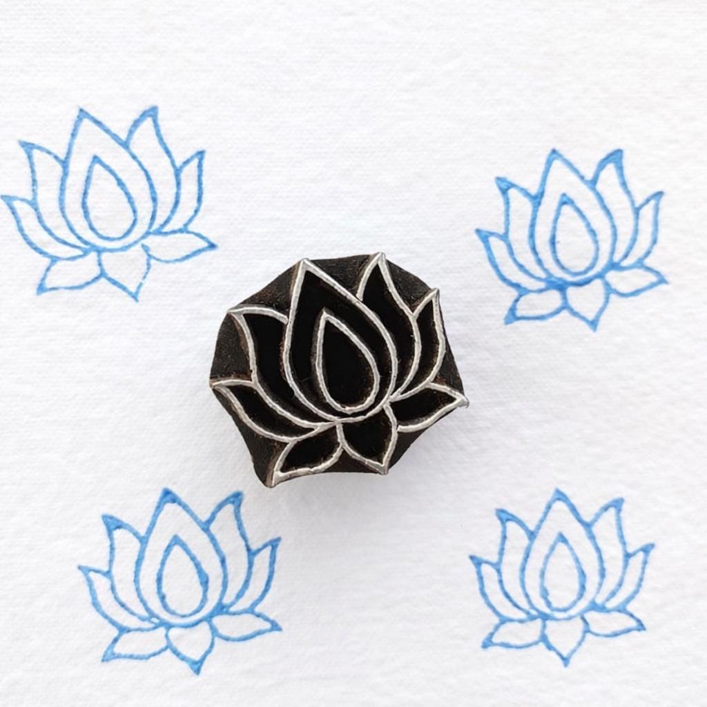 Lotus flower wooden block printing stamp creating soft blue lotus prints on white fabric paper background.