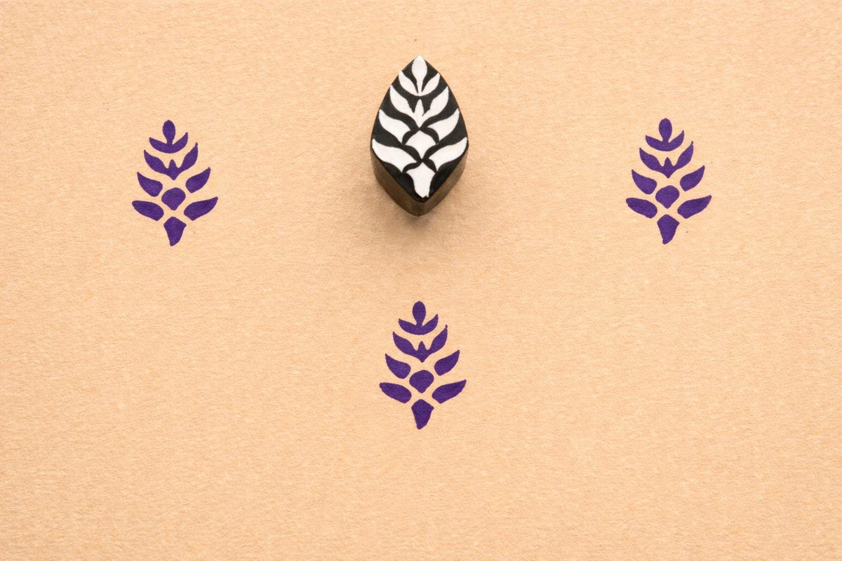 Hand carved small botanical leaf stamp printed in purple ink on textured paper