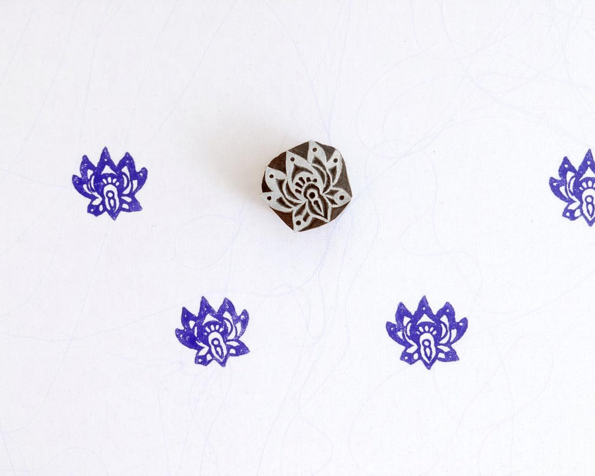 Purple small lotus flower block print pattern on white fabric using wooden stamp