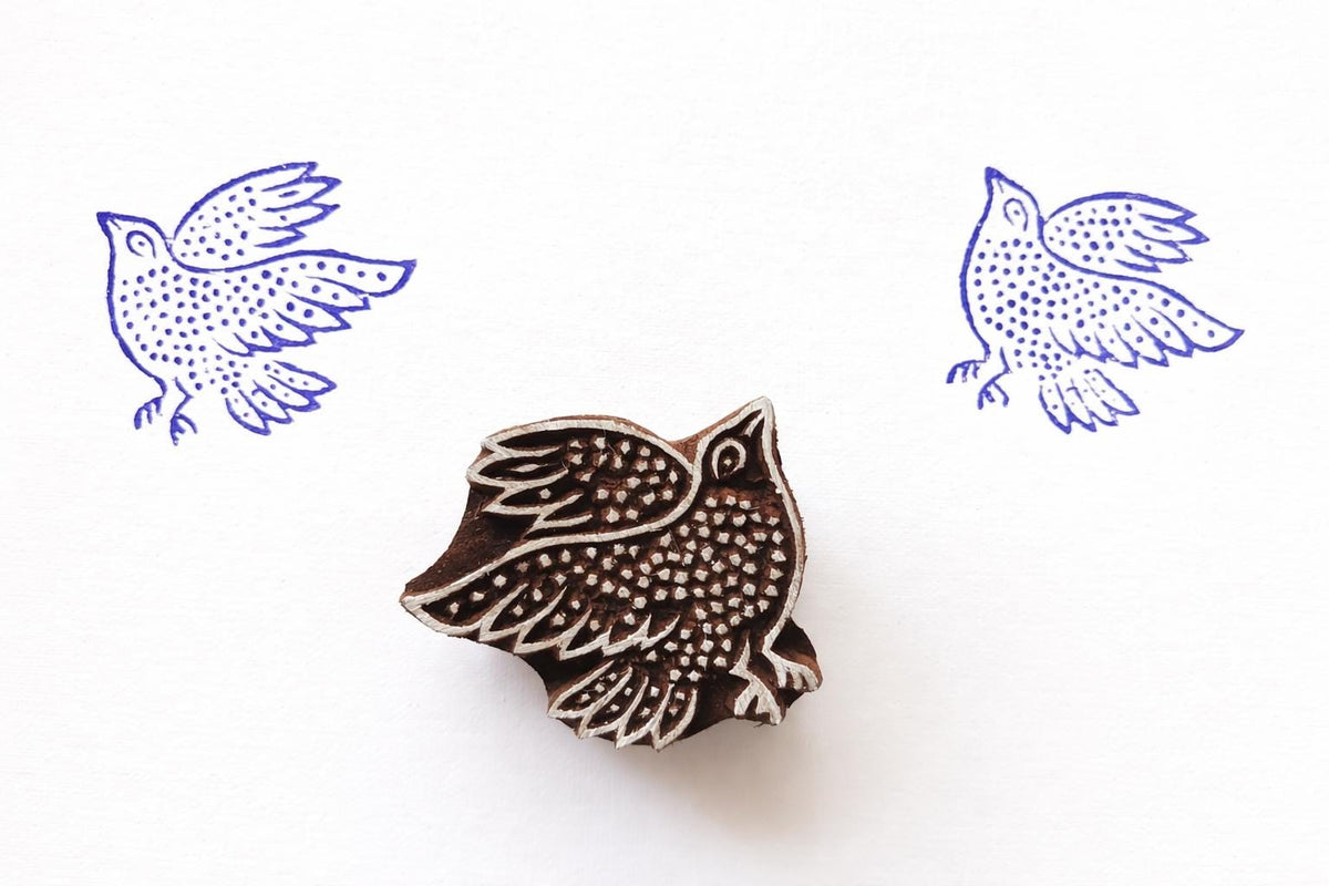 Wooden block stamp featuring a flying bird with detailed carved pattern and blue prints