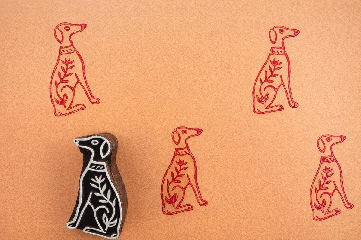 Hand-carved wooden dog block stamp with red dog prints on paper in a minimalist folk art style