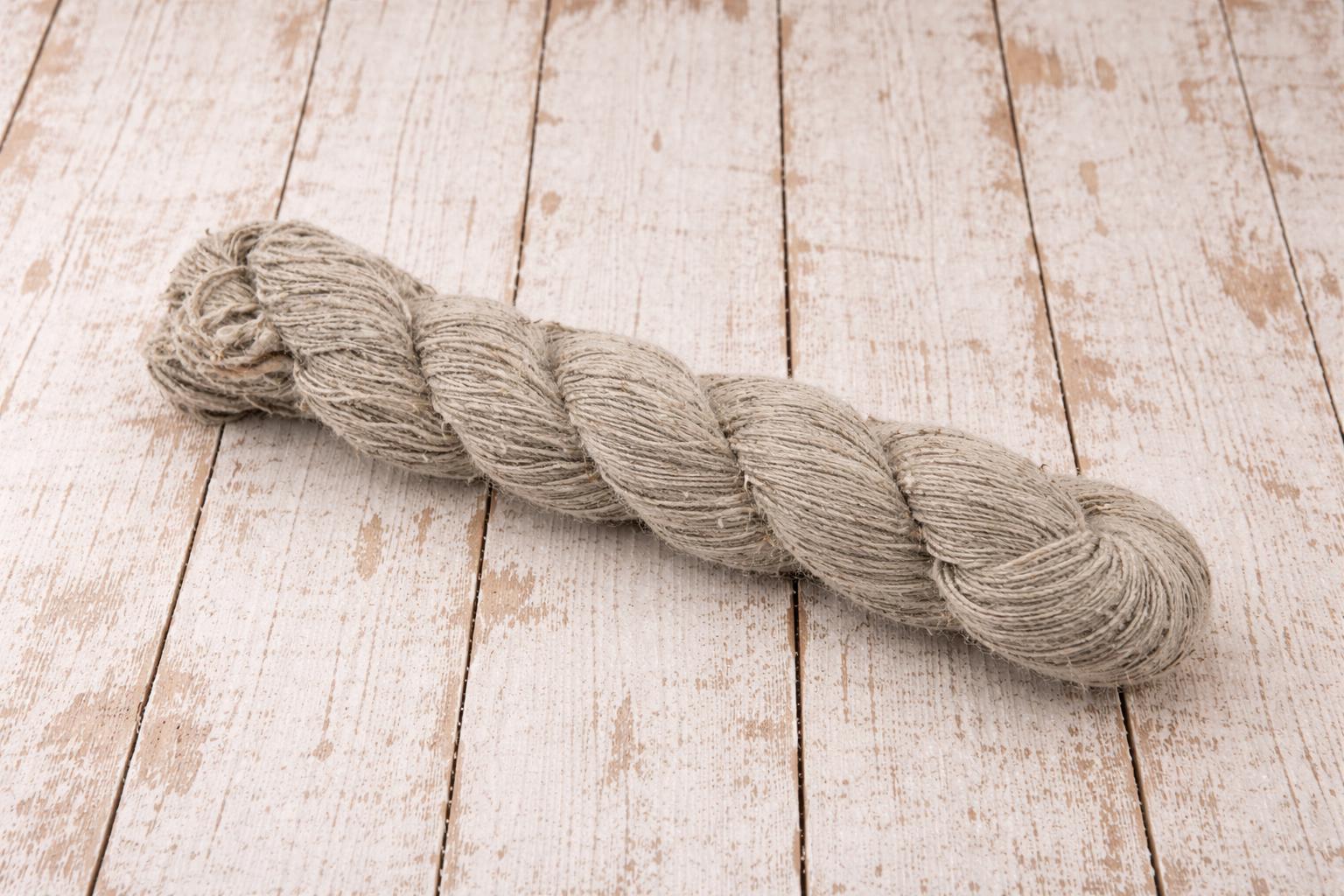 Close view of machine spun nettle wool blend yarn skein on rustic wooden background.