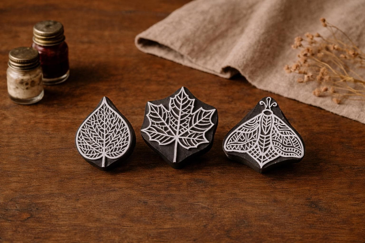 Hand carved wooden stamp set featuring Veinleaf, Crownleaf and Glyph Moth designs displayed on rustic wooden surface