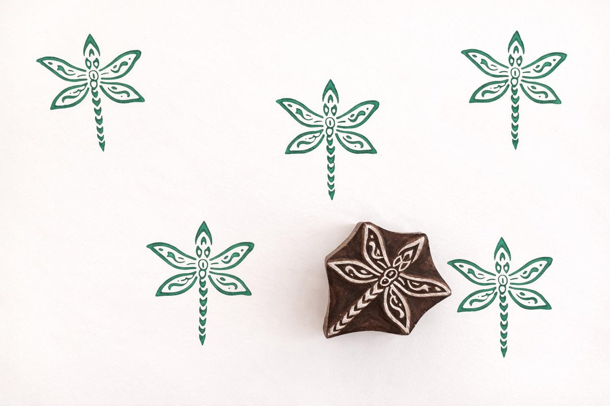 Folk art dragonfly wood stamp with green dragonfly prints on white background