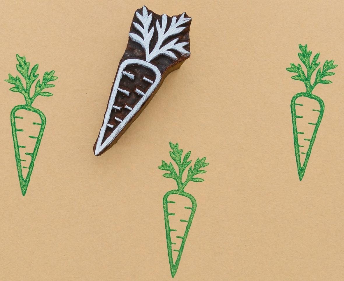 Hand carved carrot stamp with green ink prints on kraft paper