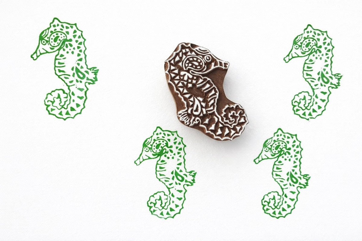 Hand carved seahorse wood block stamp with repeating printed pattern on paper