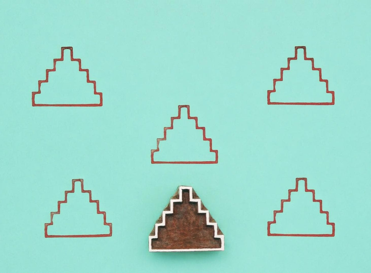 Wooden block stamp with step pyramid design shown with repeated printed pattern on teal background