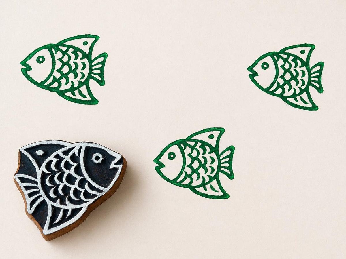 Hand carved wooden printing block with a simple fish illustration for coastal themed fabric printing and repeat patterns.