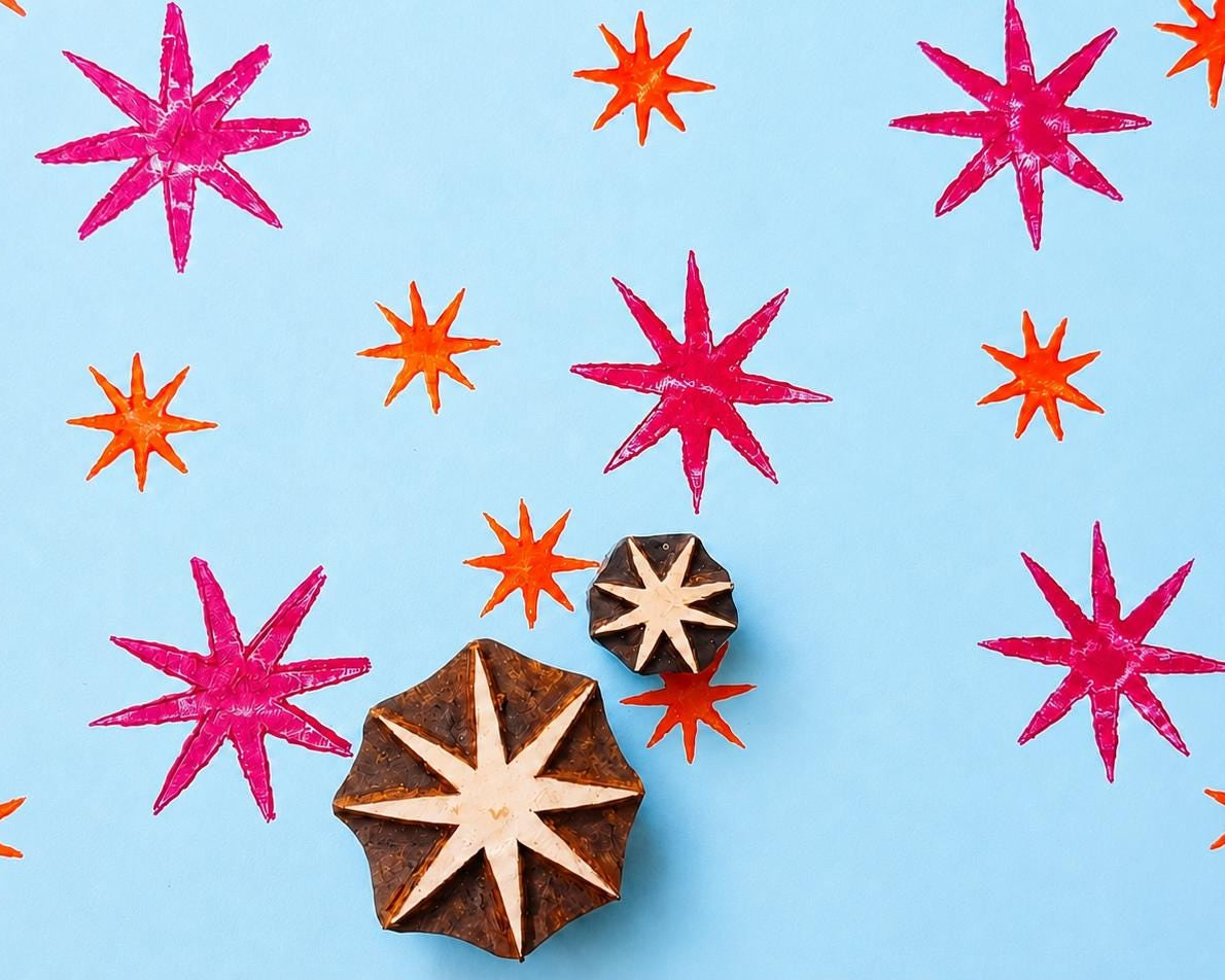 Hand carved Indian wooden printing block set featuring bold celestial starburst patterns printed in pink and orange on blue background for textile printing, pottery, clay, and paper crafts.