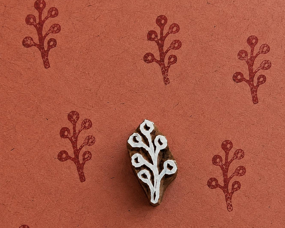 Tiny hand carved winter berry sprig block stamp with repeating botanical berry branch impressions on handmade paper