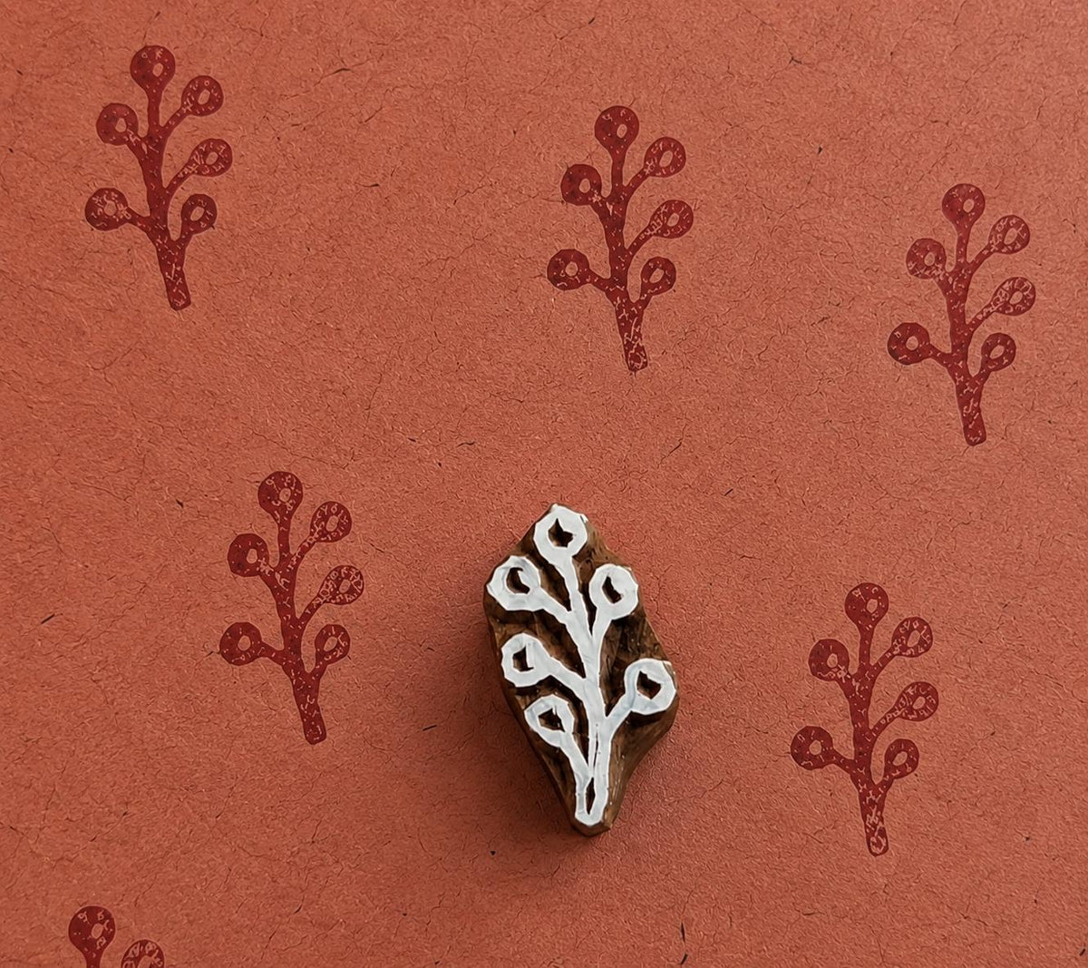 Tiny hand carved winter berry sprig block stamp with repeating botanical berry branch impressions on handmade paper