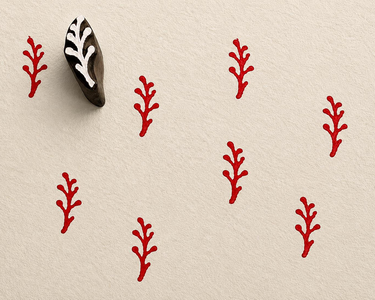 Tiny hand carved berry stem block stamp with repeating red botanical branch impressions on textured paper