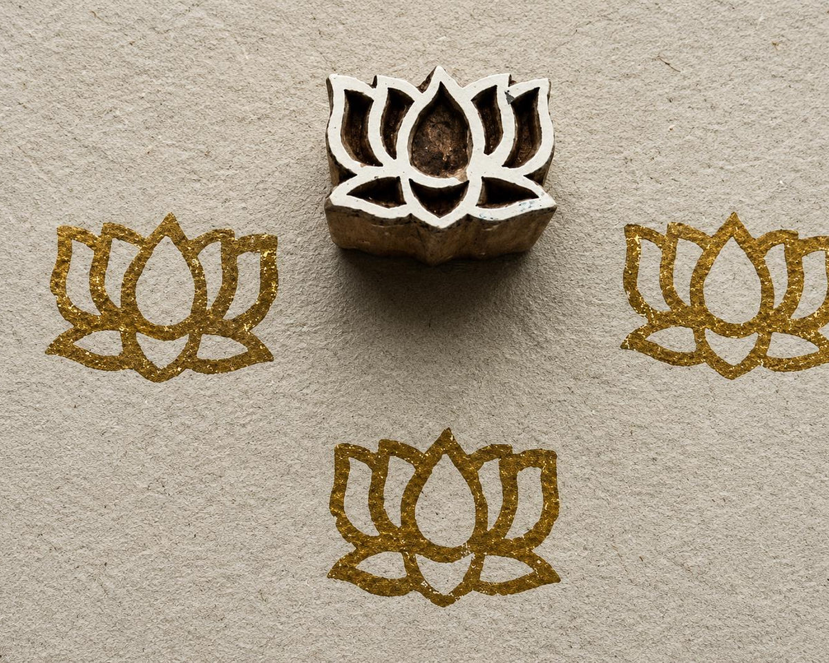 Hand carved Temple Lotus wooden block stamp with metallic gold lotus impressions on textured handmade paper.