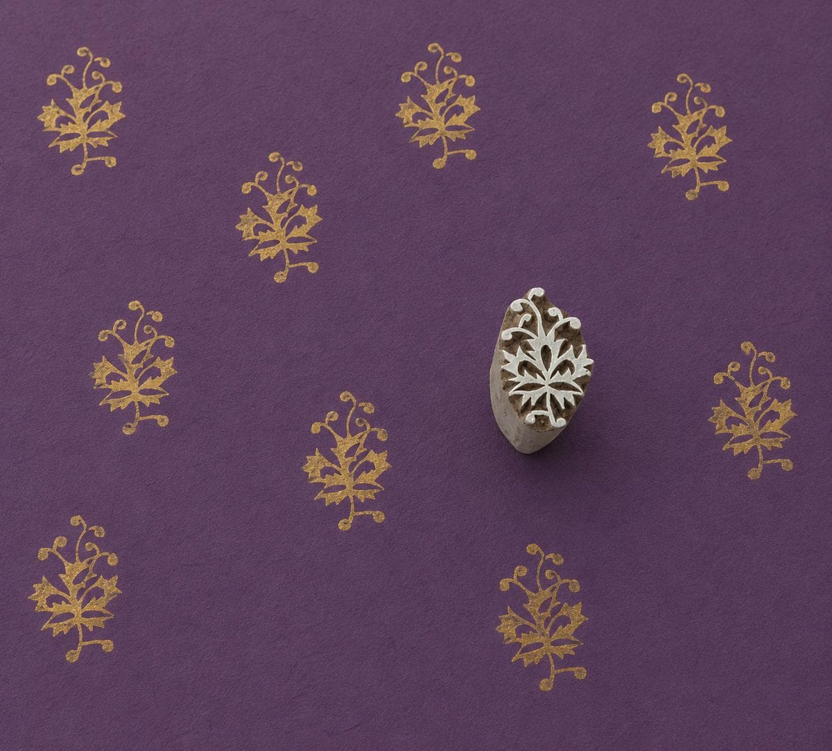 Hand carved Ornamental Vine wooden block stamp with metallic gold impressions on deep purple handmade paper.