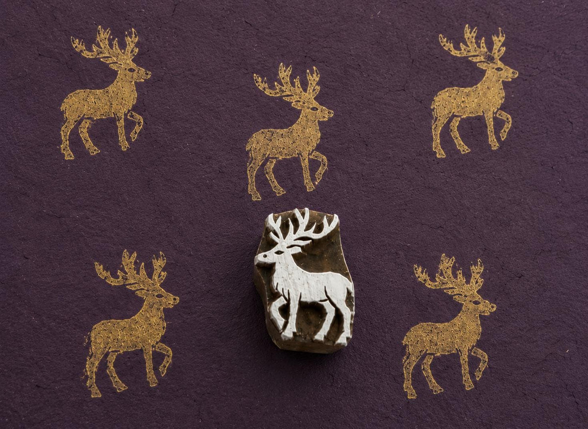 Majestic stag wooden block stamp creating golden deer impressions on textured handmade paper.